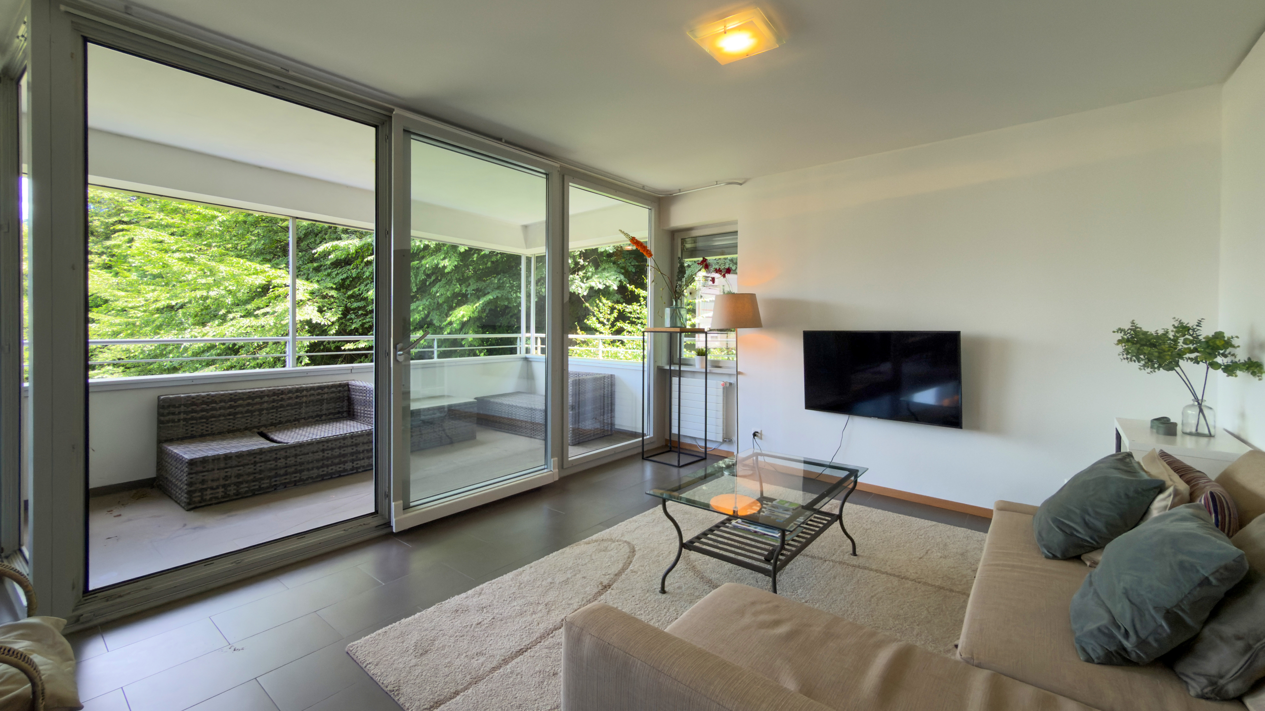 Helles Wohnzimmer mit großer Fensterfront und Balkon