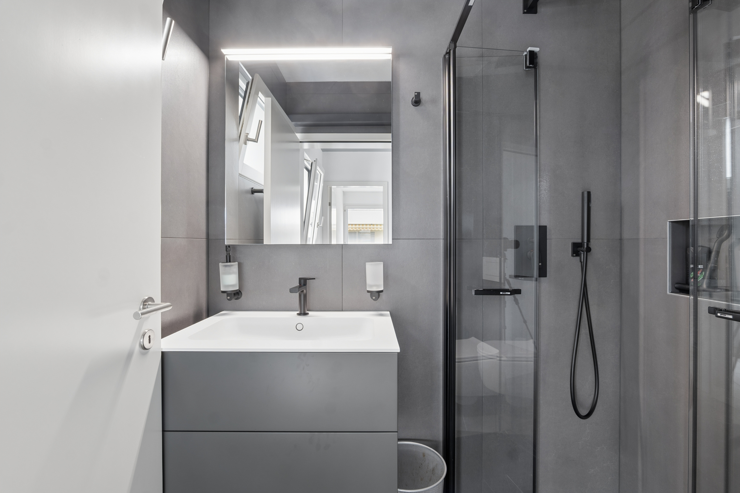 Modernes Badezimmer mit dunkler Dusche und Waschtisch