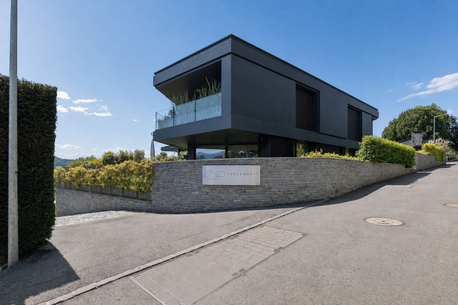 Modernes Einfamilienhaus mit dunkler Fassade an einer Hanglage