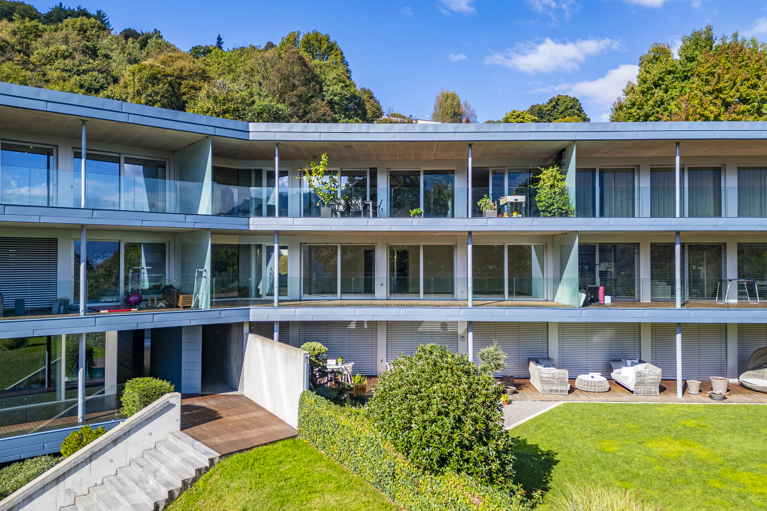 Moderne Mehrfamilienhausfassade mit Balkonen und Garten