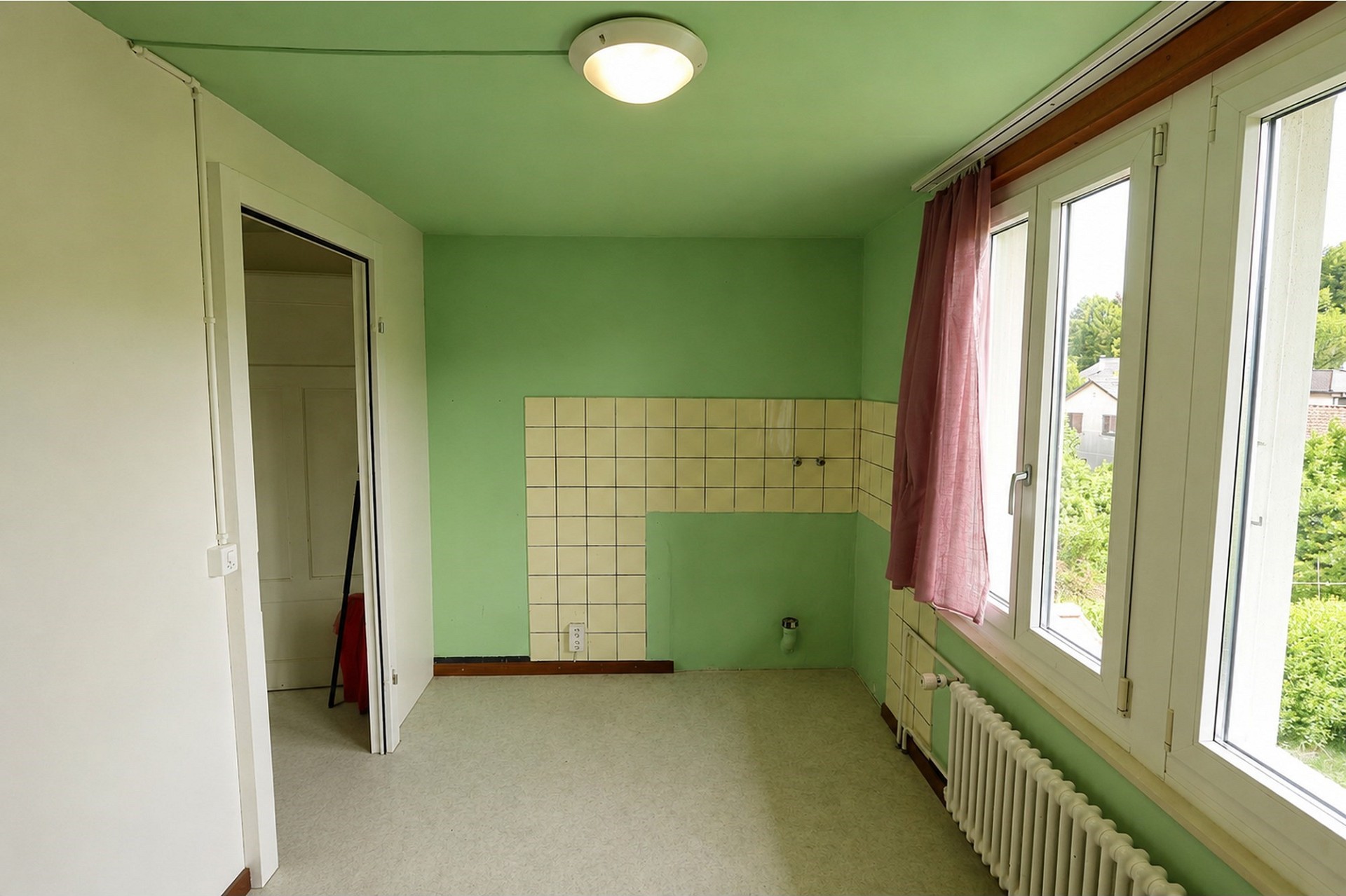 Leerer Raum mit grün gestrichenen Wänden und großer Fensterfront