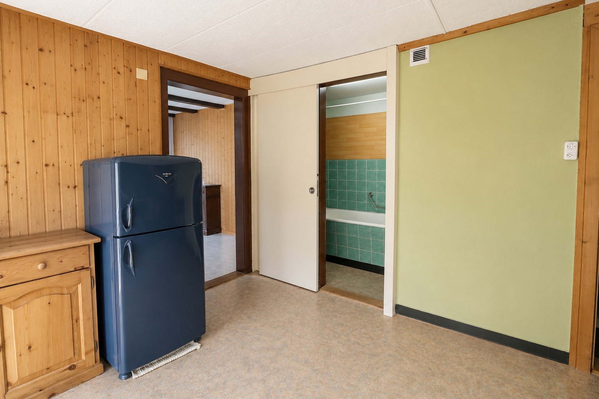 Kleiner Innenraum mit Holzverkleidung und Retro-Kühlschrank