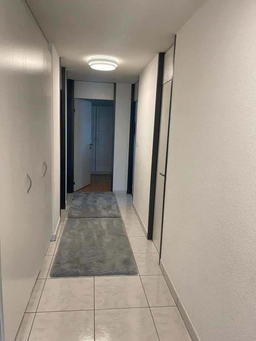 Flur mit hellen Fliesen und Teppichläufern