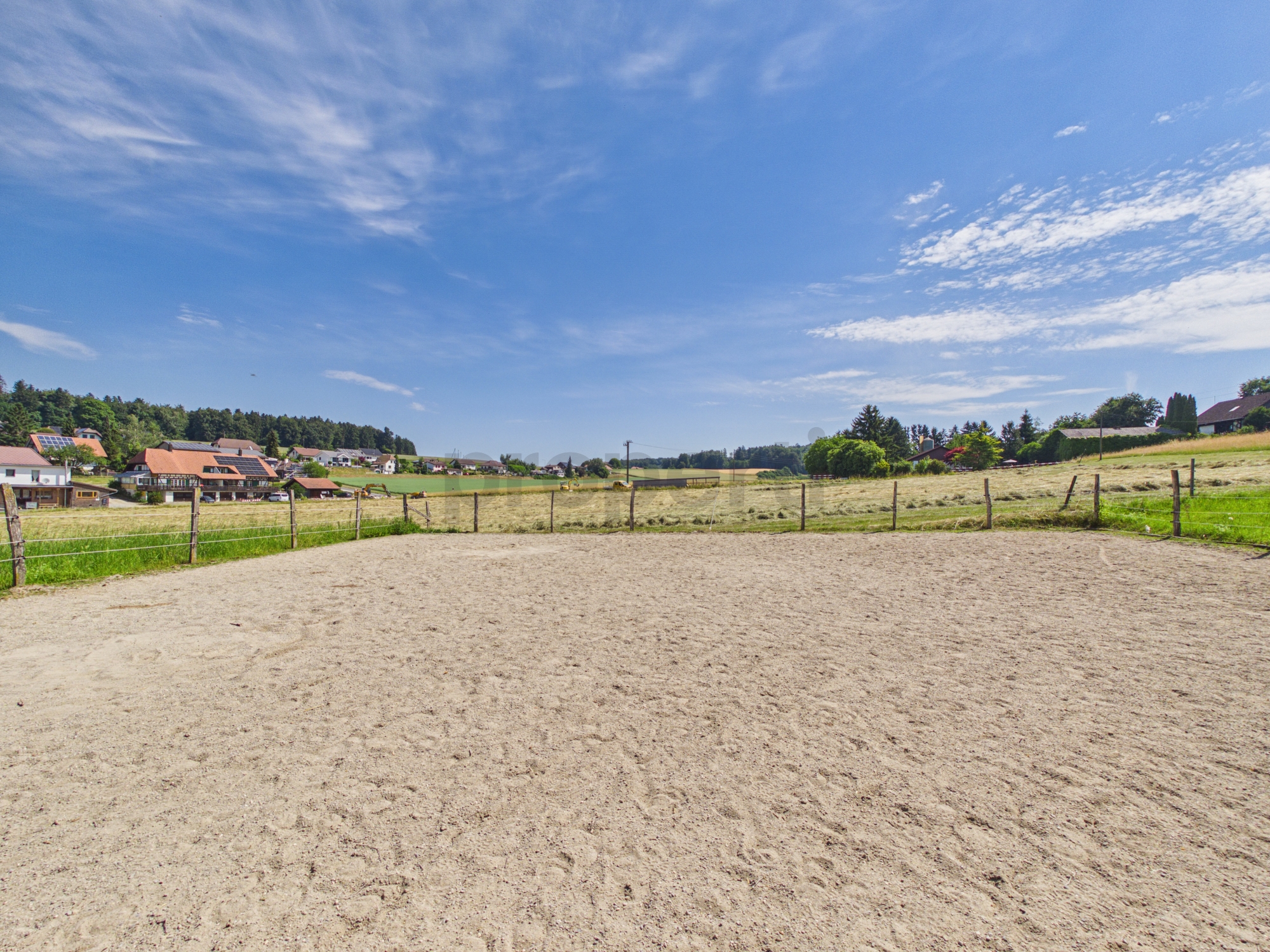 Ländliche Wiese mit eingezäuntem Sandplatz