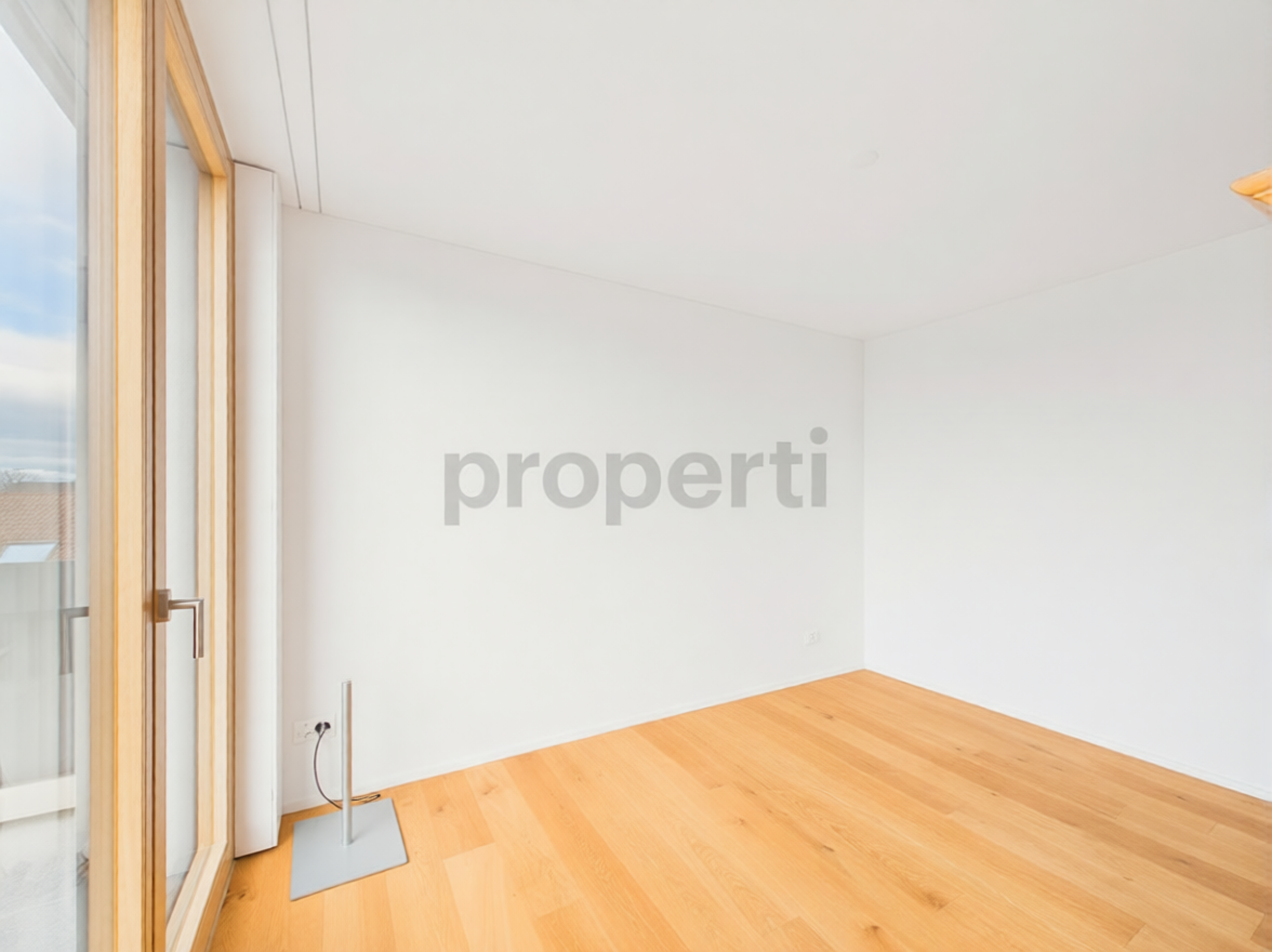 Heller leerer Wohnraum mit Holzboden und bodentiefem Fenster