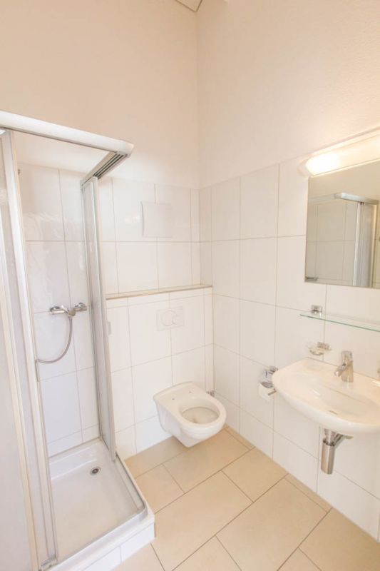 Kleines weißes Badezimmer mit Dusche, WC und Waschbecken