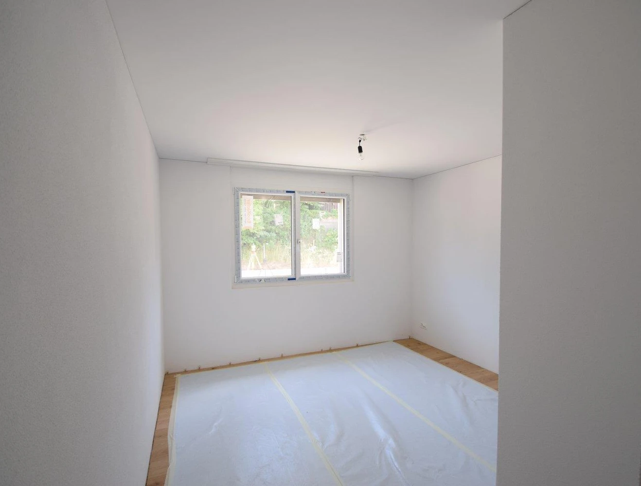 Leeres, frisch gestrichenes Zimmer mit Fenster