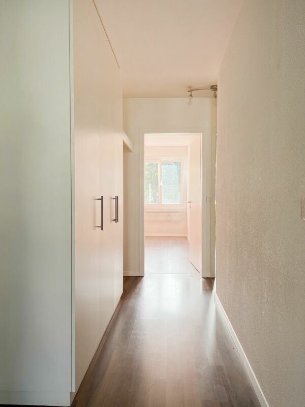 Schmaler Flur mit Einbauschrank und Blick in einen hellen Raum