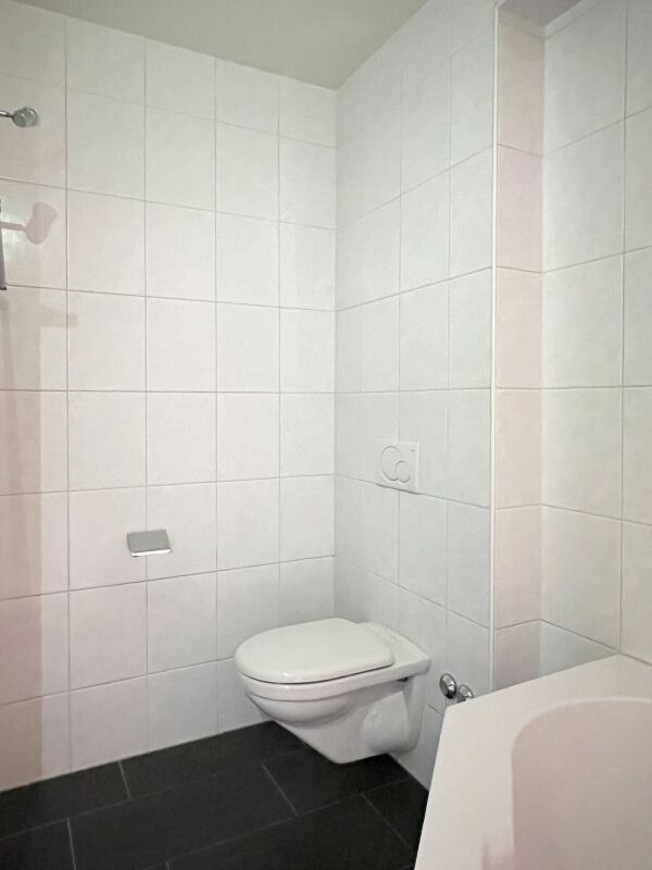 Kleines weiß gefliestes Badezimmer mit WC