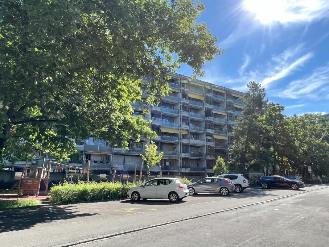 Mehrfamilienhaus mit Balkonfront an einer sonnigen Wohnstraße