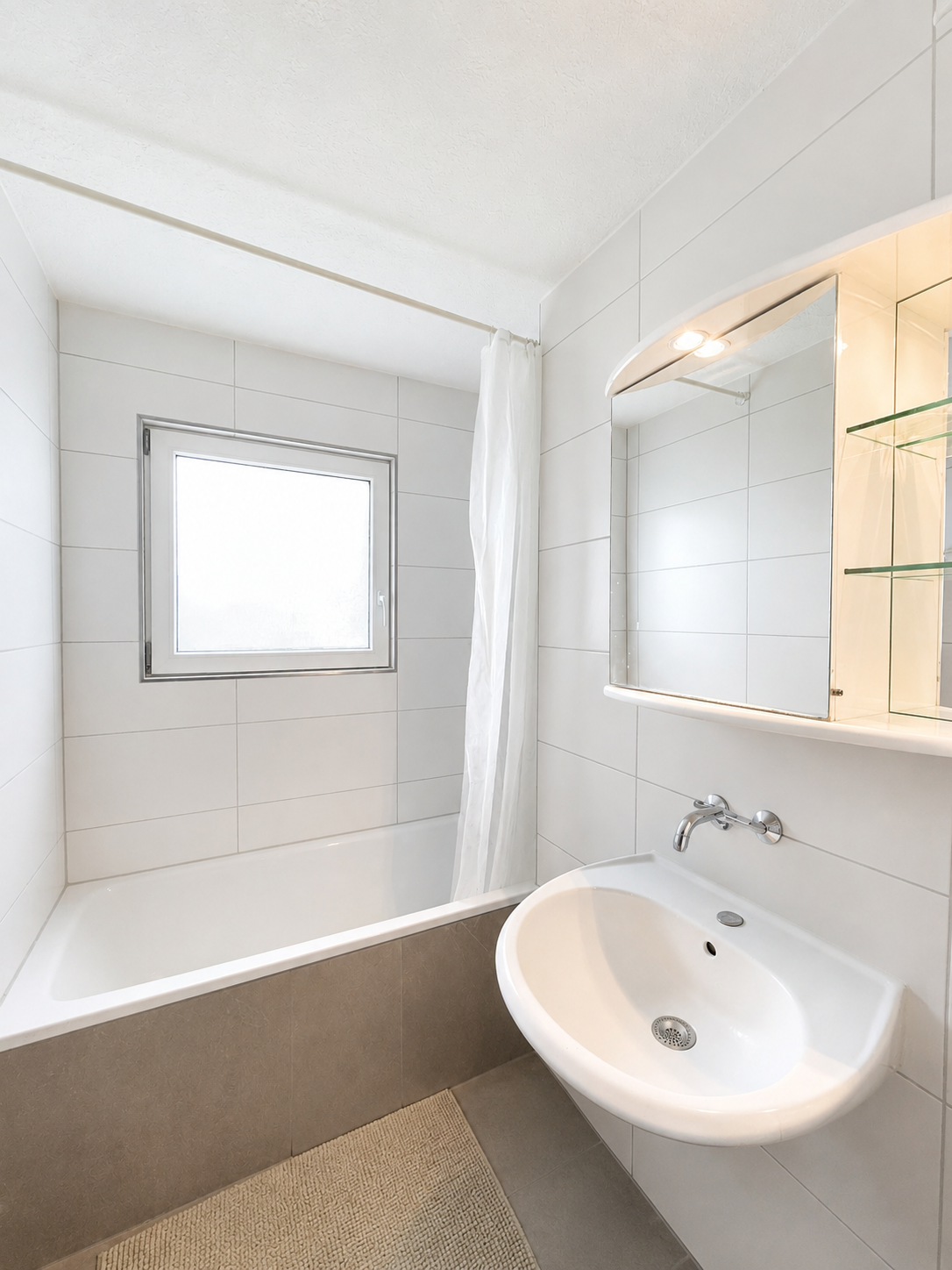 Kleines weißes Badezimmer mit Badewanne und Waschtisch