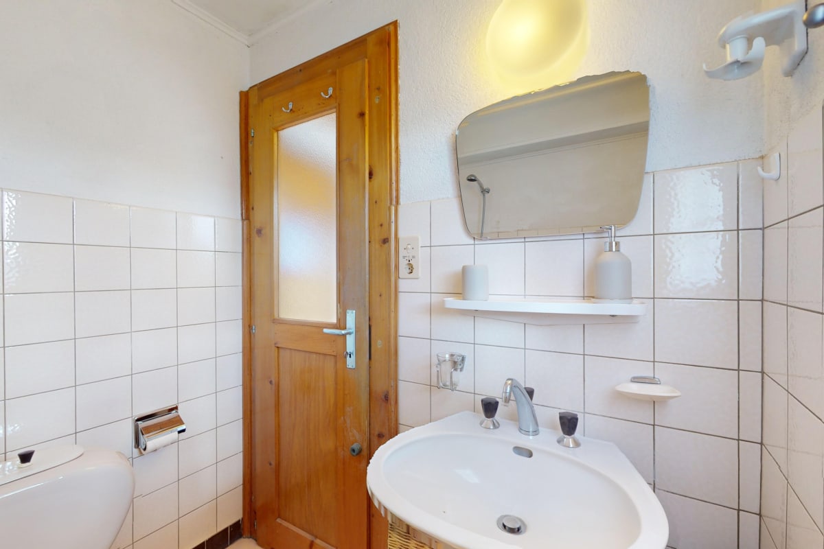 Gäste-WC mit Holz­tür und Waschbecken