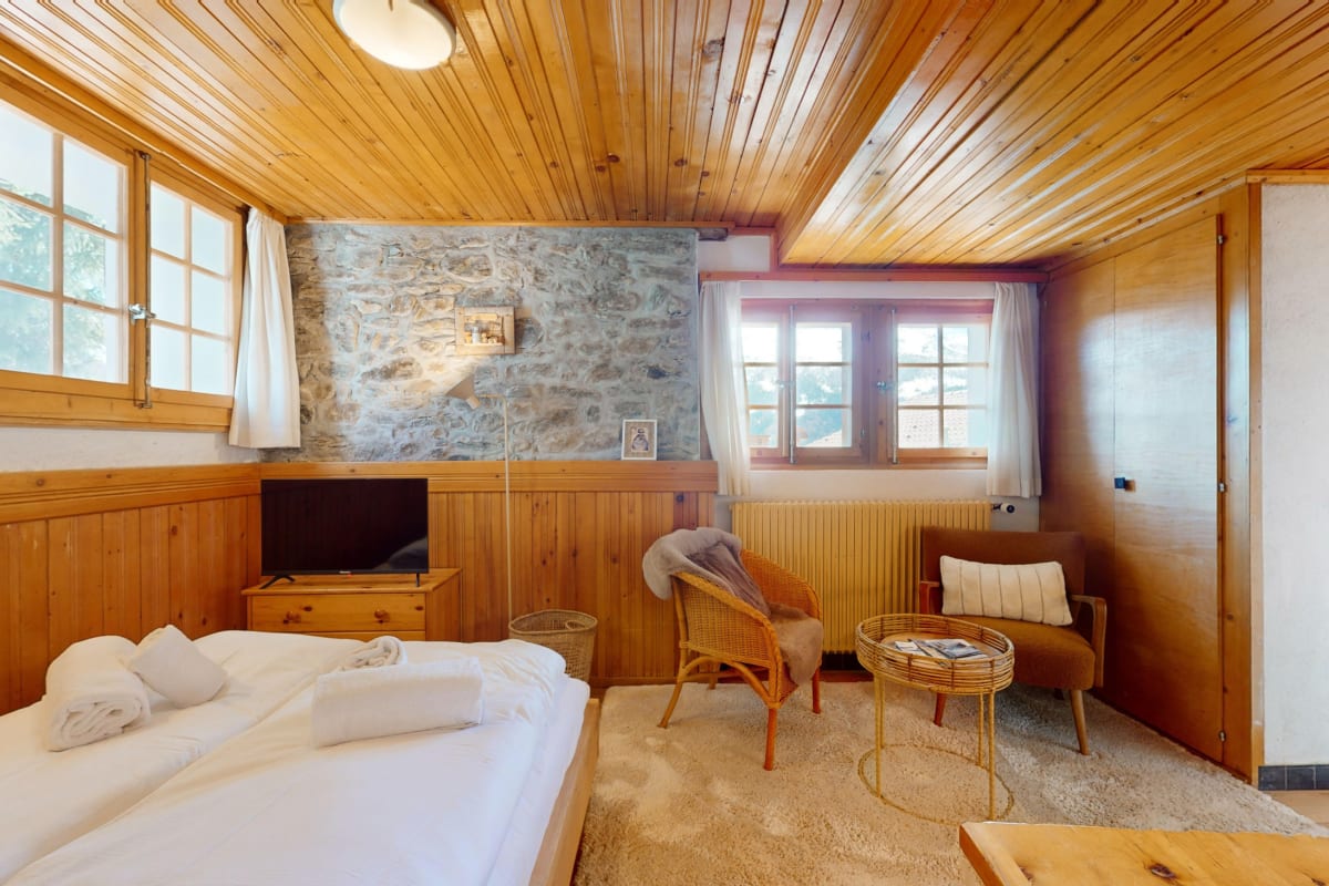Gemütliches Schlafzimmer mit Holzvertäfelung und Natursteinwand