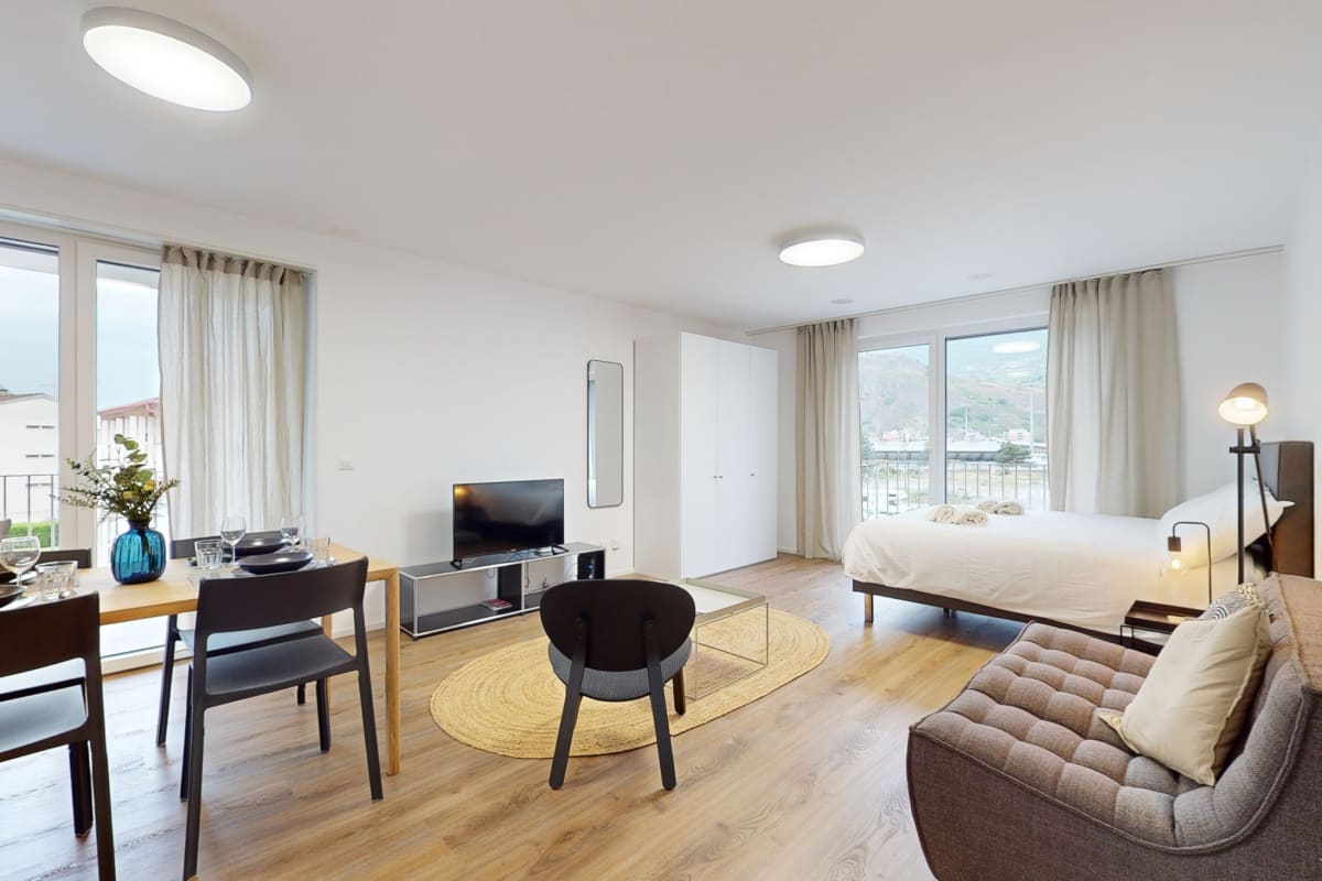 Helles Studio mit Bett, Essbereich und Balkonblick