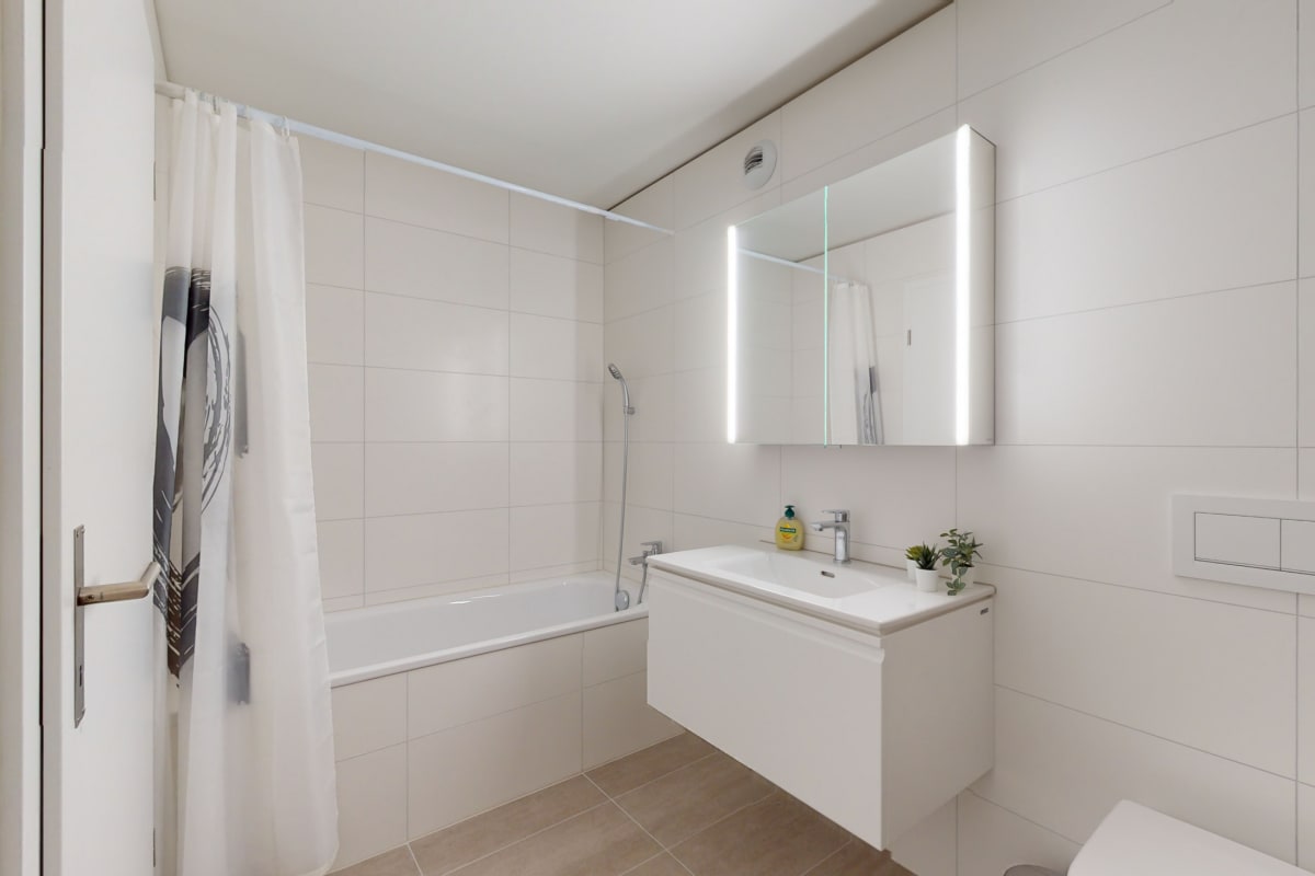 Modernes Badezimmer mit Wanne und beleuchtetem Spiegel