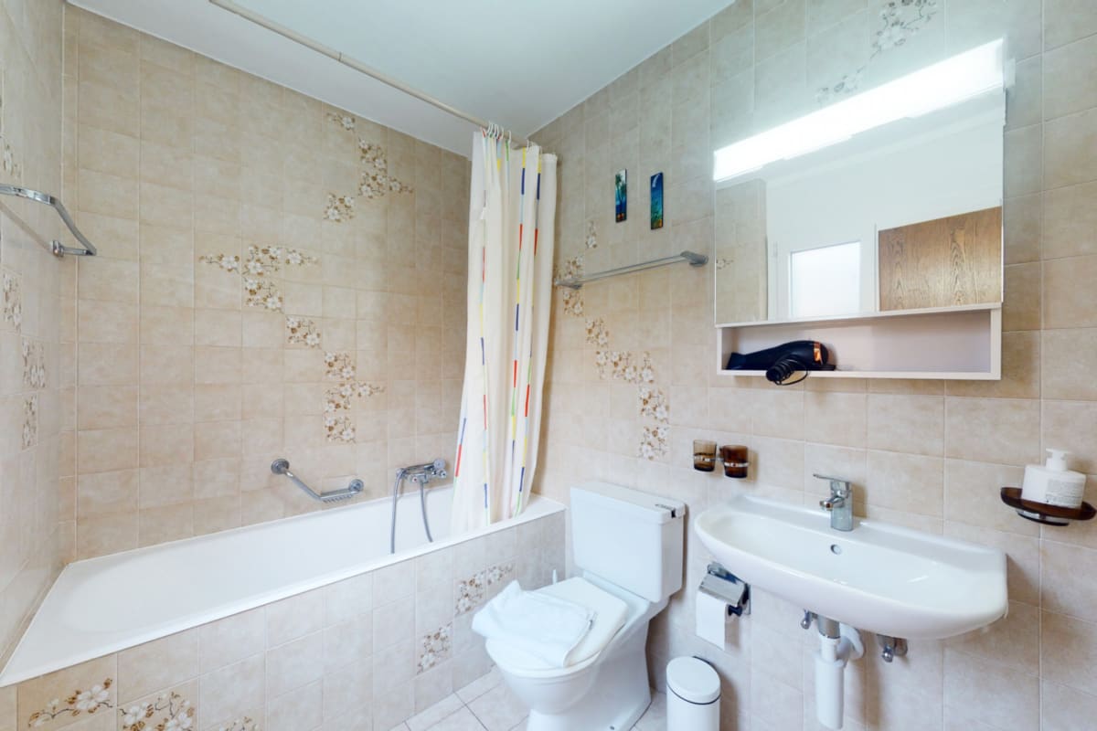 Helles Badezimmer mit Badewanne, Waschtisch und Spiegel