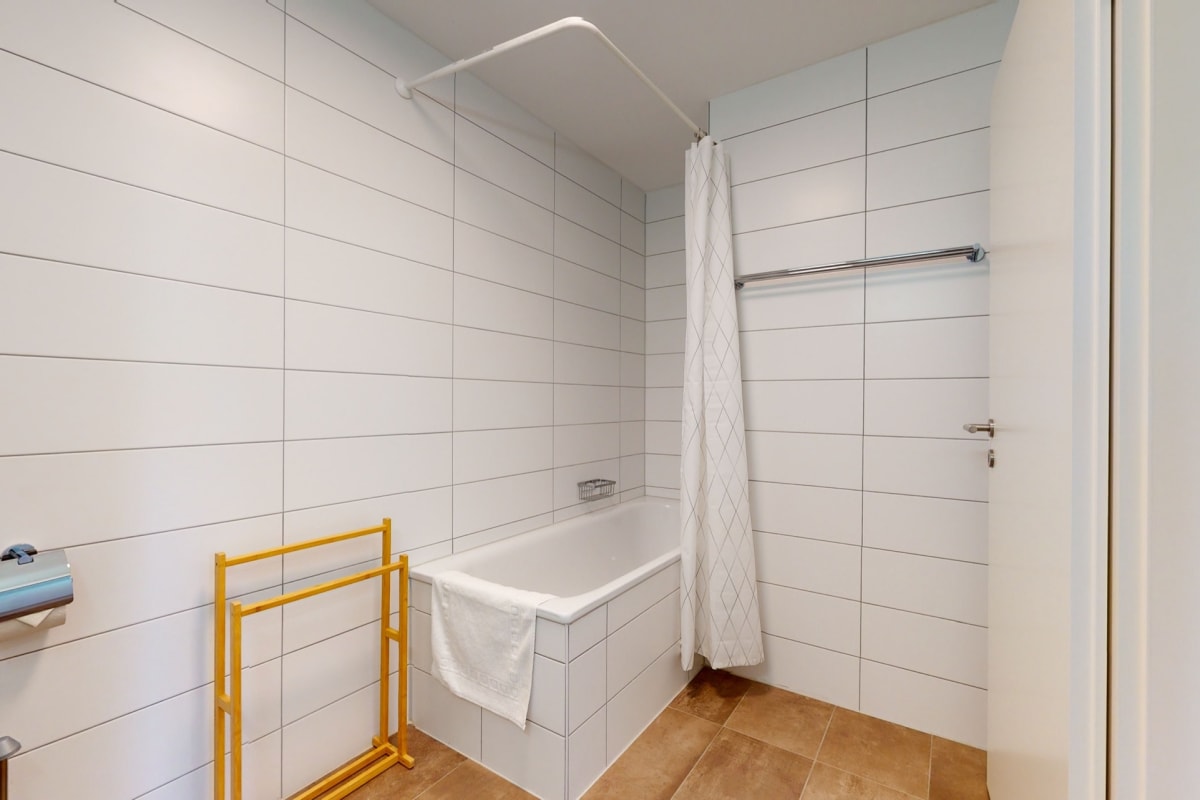 Badezimmer mit Badewanne und weißen Wandfliesen