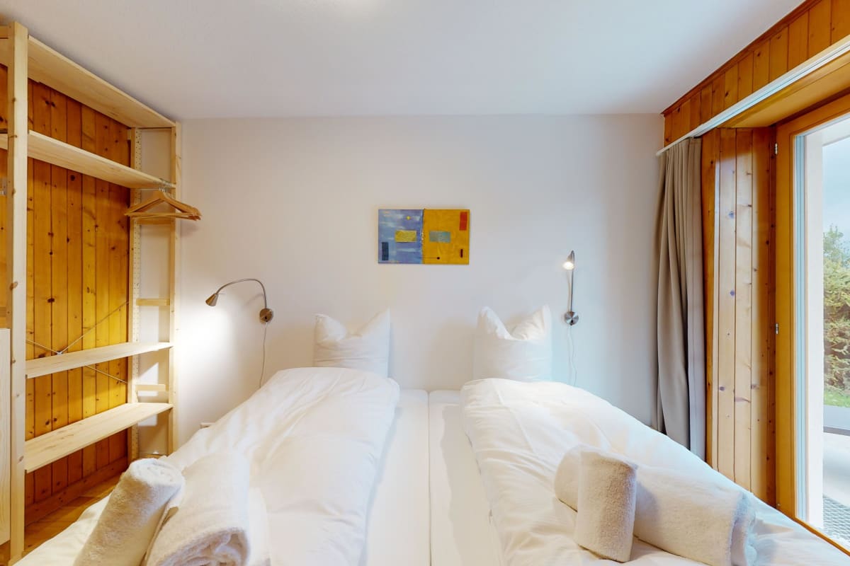Helles Schlafzimmer mit zwei Einzelbetten und Holzverkleidung