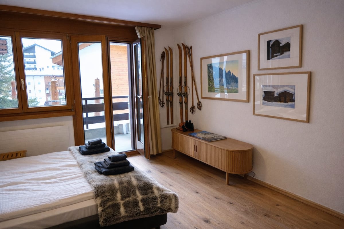 Gemütliches Schlafzimmer im alpinen Stil mit Balkonblick