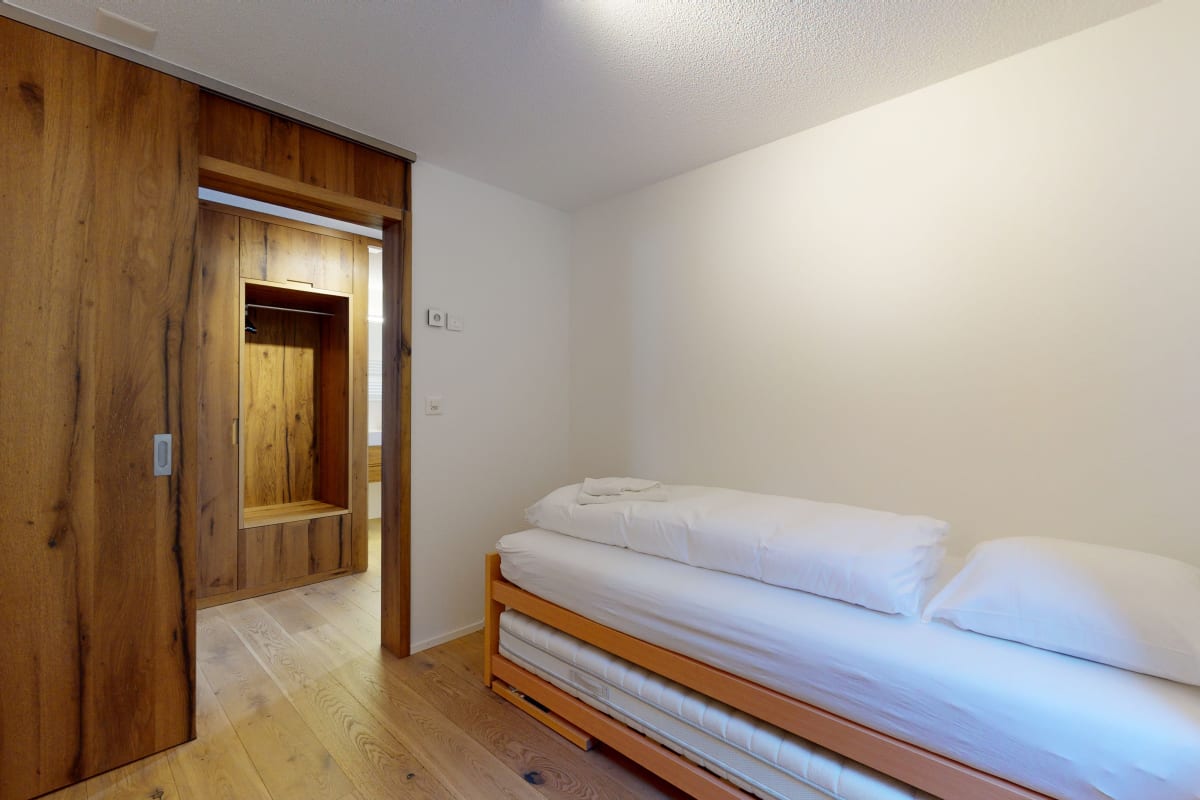 Schlafzimmer mit Einzelbett und Holzschrank