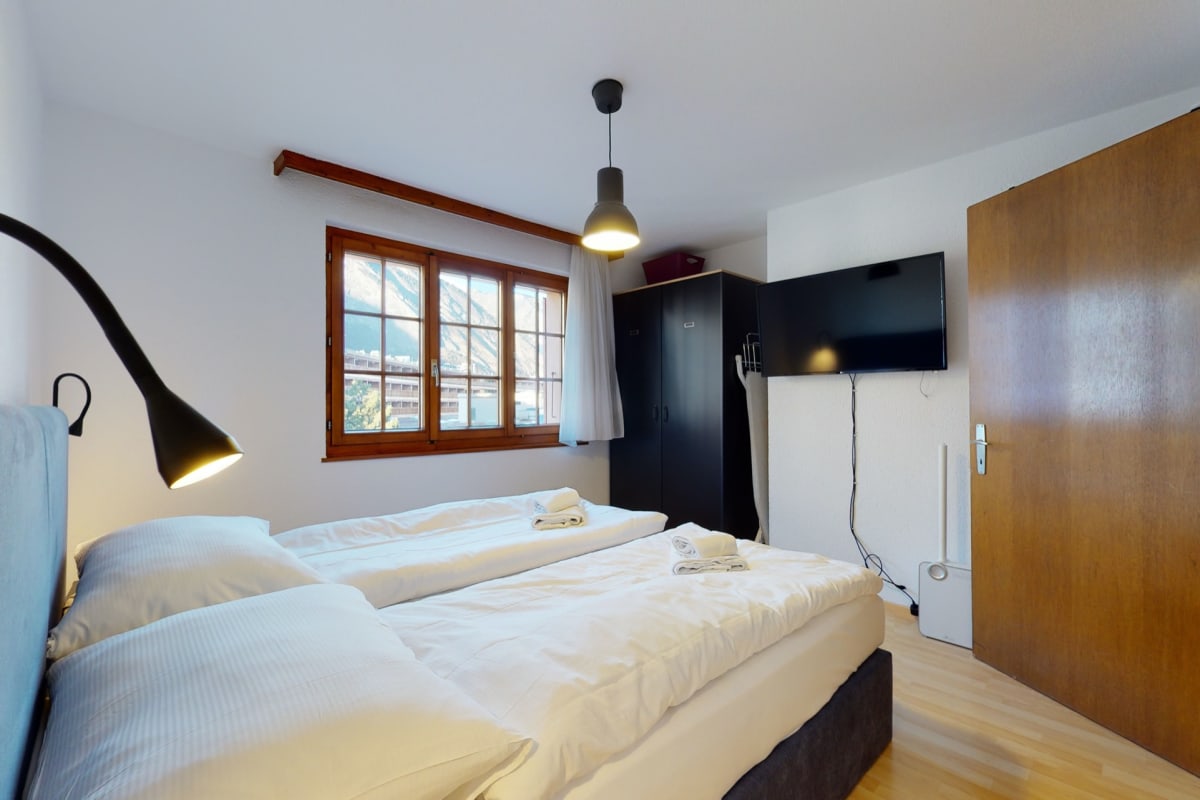 Helles Schlafzimmer mit zwei Betten und Bergblick