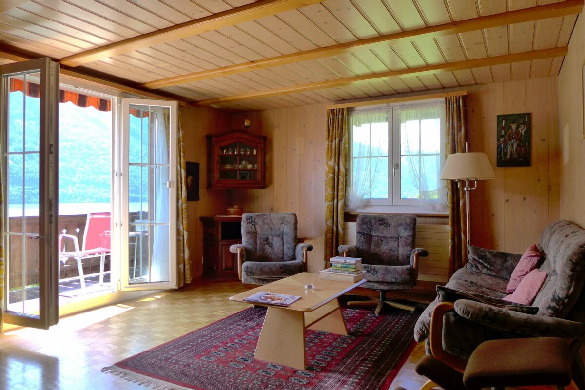 Gemütliches Wohnzimmer mit Holzverkleidung und Balkonzugang