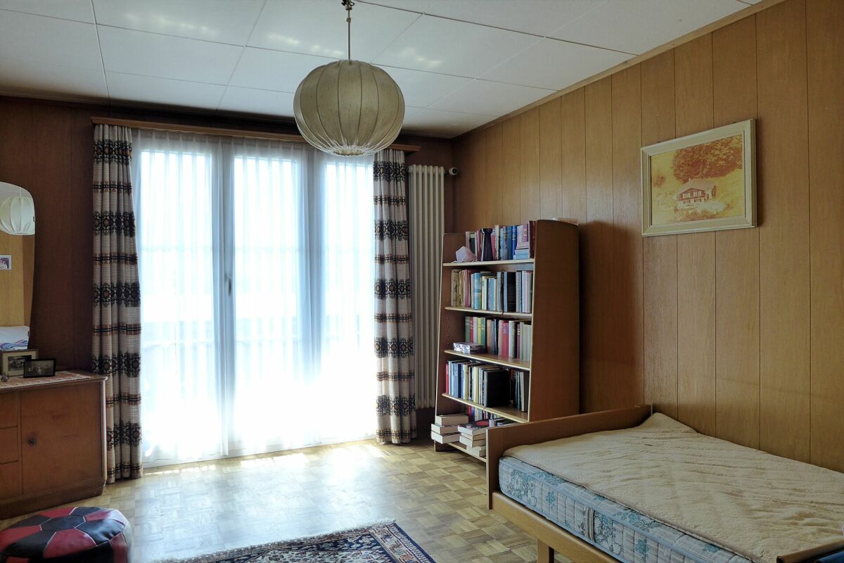 Schlafzimmer mit Holzvertäfelung und Balkonfenster