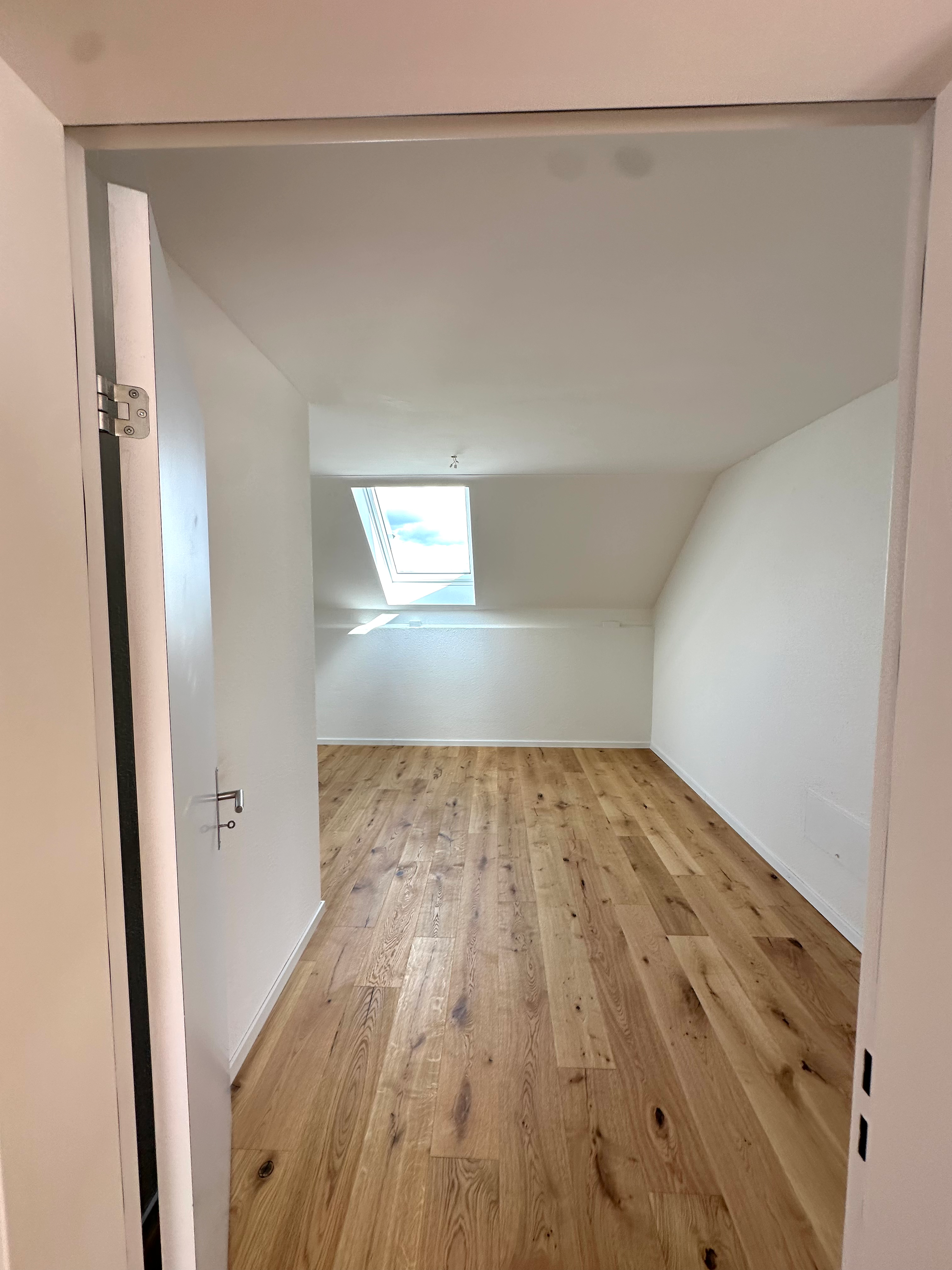 Heller Dachraum mit Holzparkett und Dachfenster