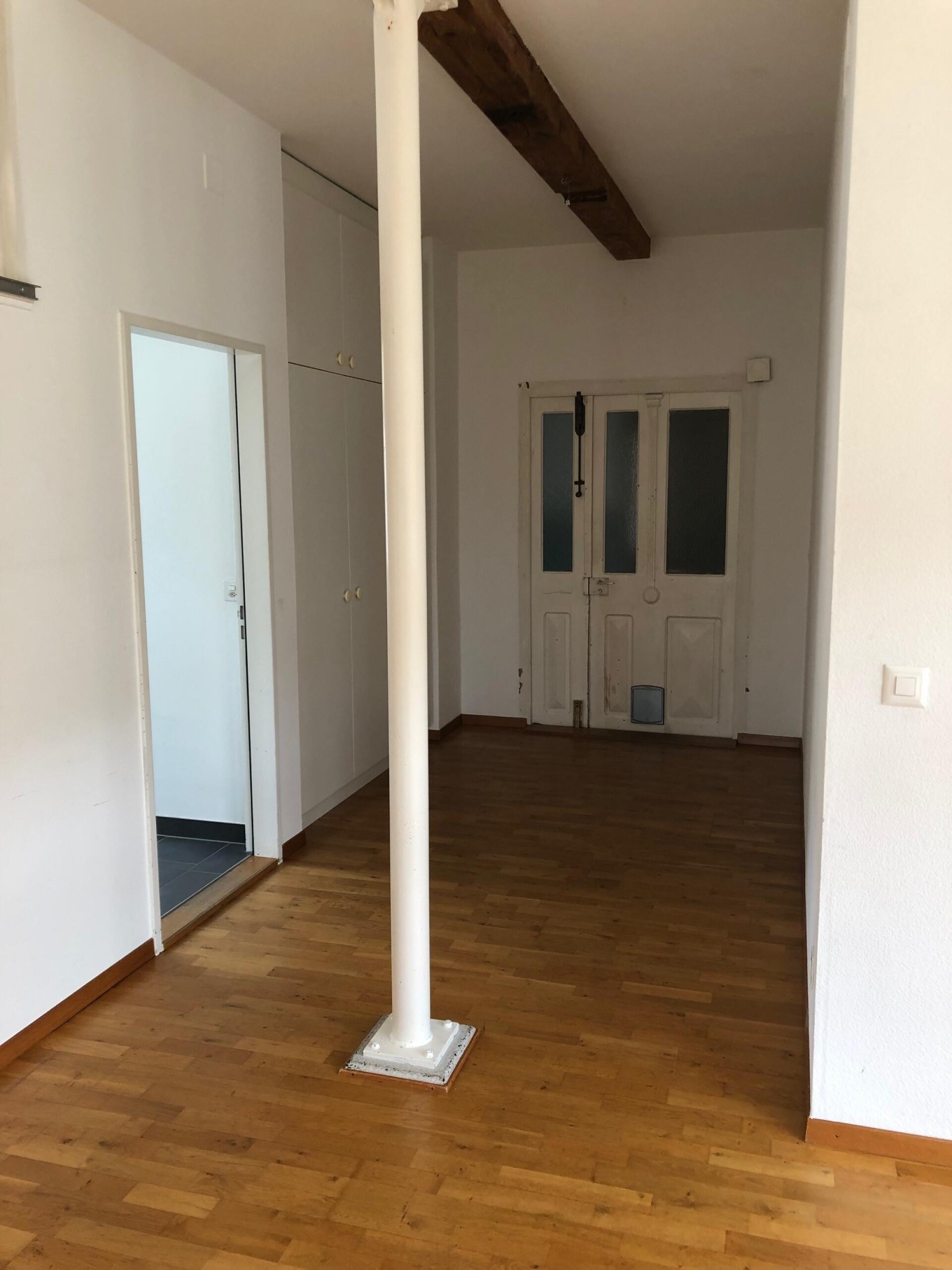 Heller Innenraum mit Holzboden und sichtbarem Stahlstützen