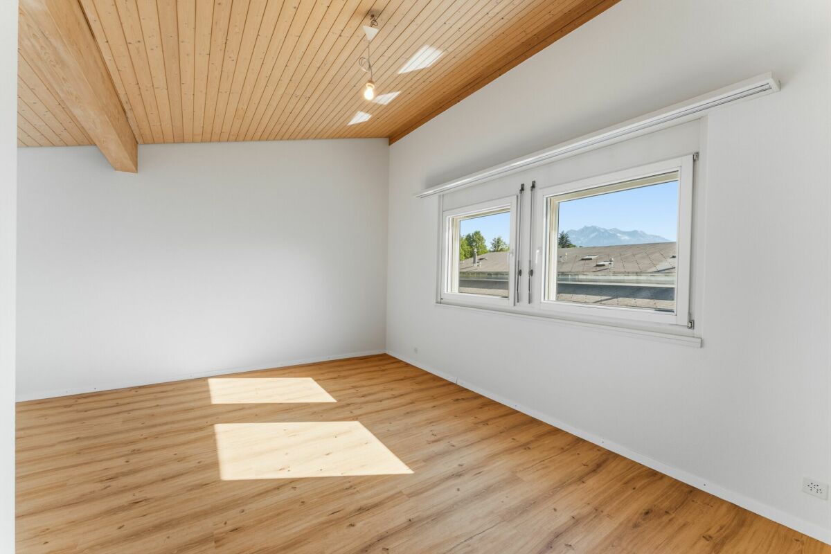 Heller leerer Raum mit Holzdecke und Blick ins Gebirge