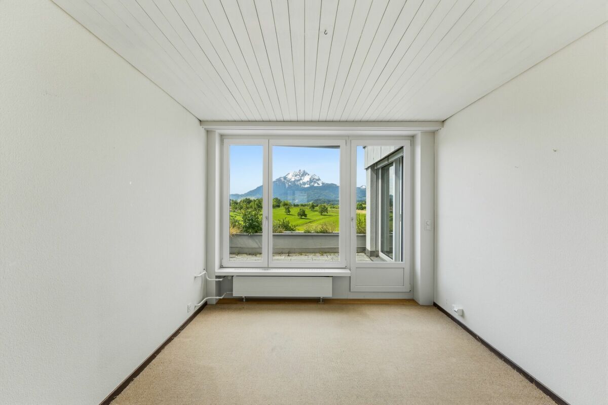 Heller leerer Raum mit großem Fenster und Alpenblick