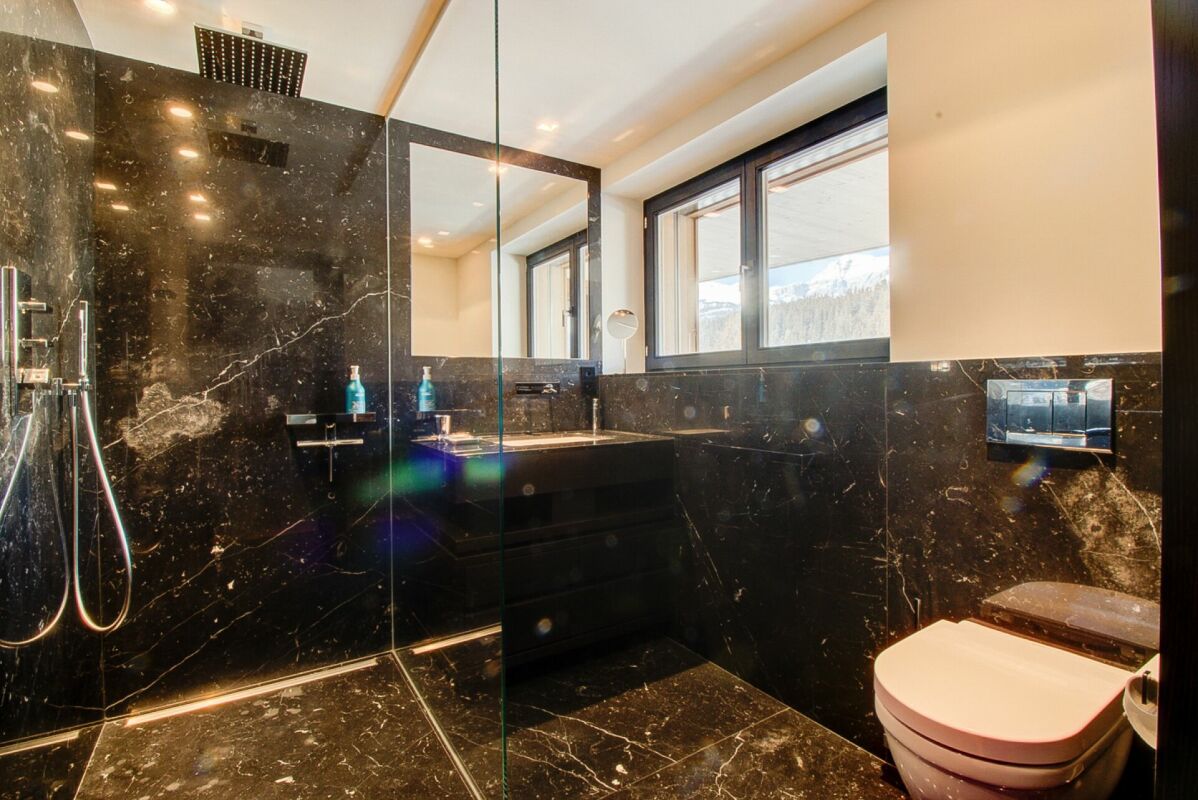 Modernes Badezimmer mit schwarzer Natursteinoptik und Aussicht auf die Berge