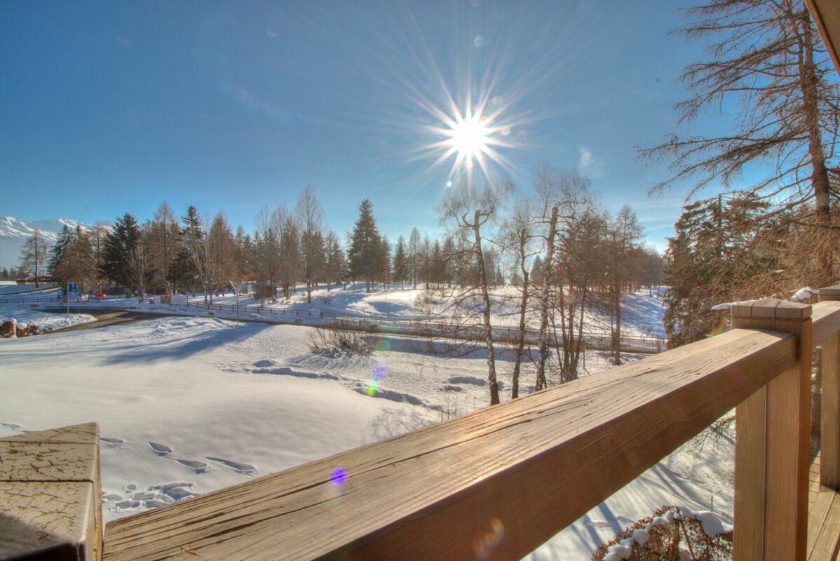 Schneebedeckte Landschaft mit sonnigem Ausblick von einer Holzterrasse
