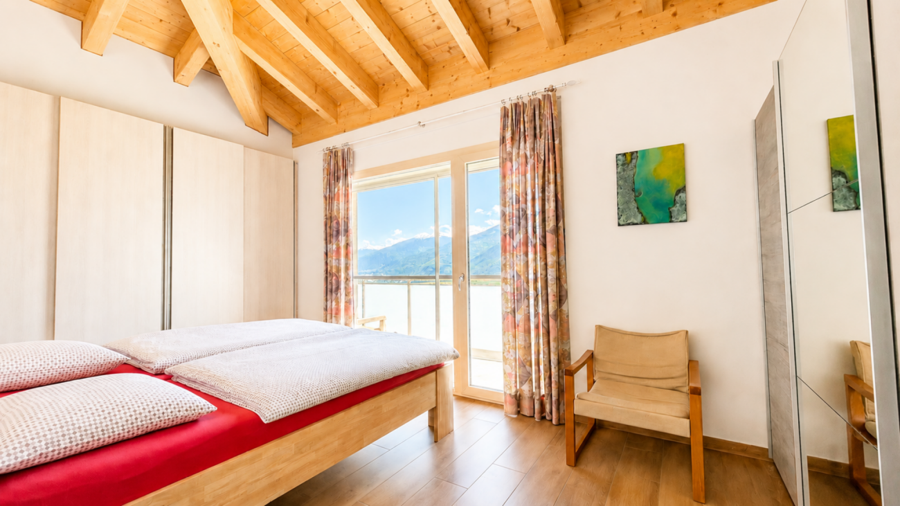 Helles Schlafzimmer mit Holzbalkendecke und Bergblick