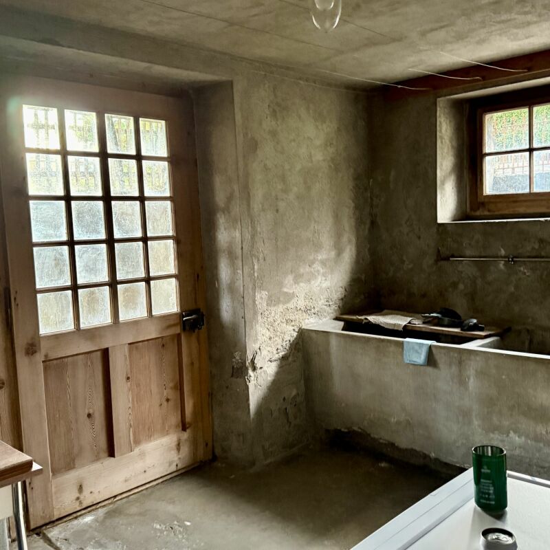 Rustikaler Innenraum mit Holztür und kleinem Fenster