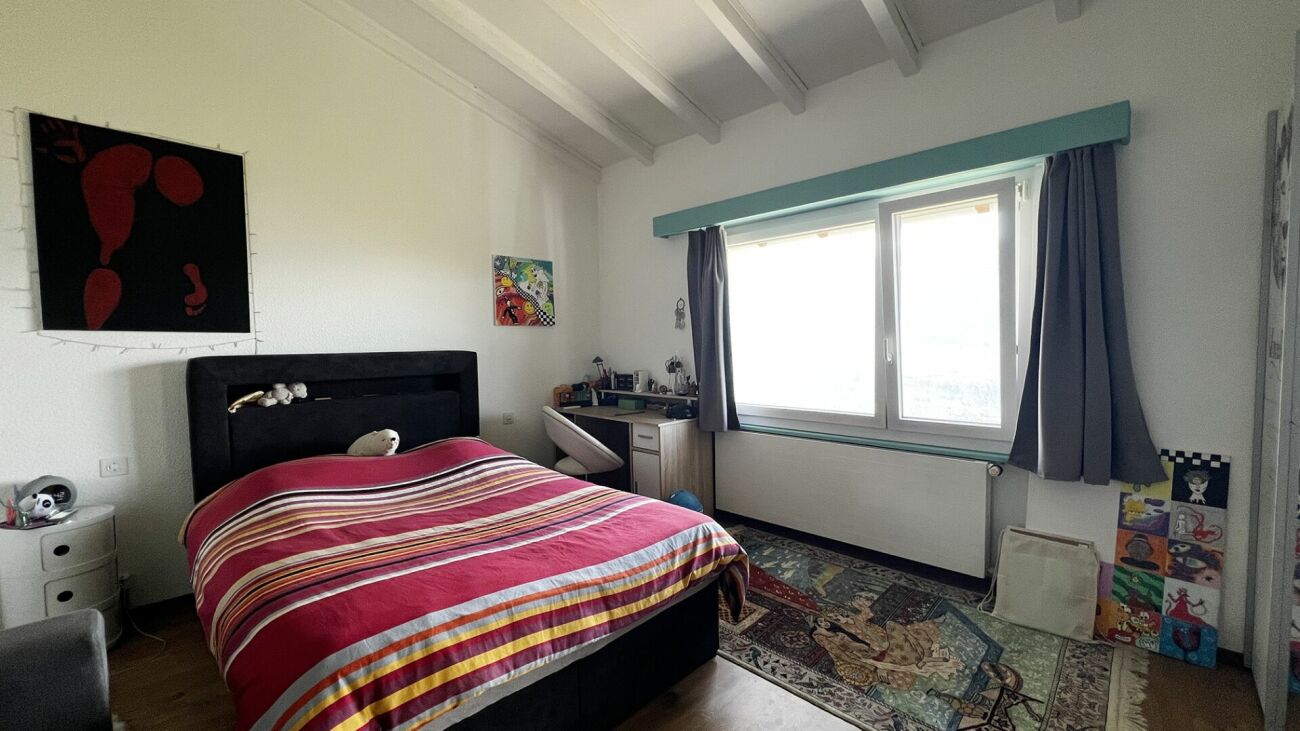 Helles Schlafzimmer mit großem Fenster und Arbeitsplatz