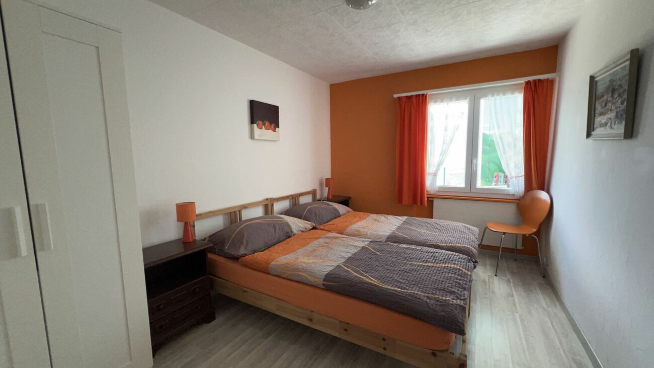 Schlafzimmer mit Doppelbett und orangefarbenen Akzenten