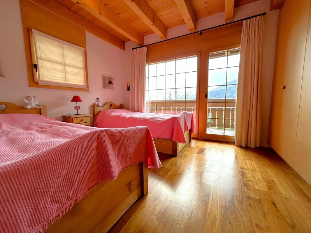 Helles Schlafzimmer mit Holzbalkendecke und Balkonblick