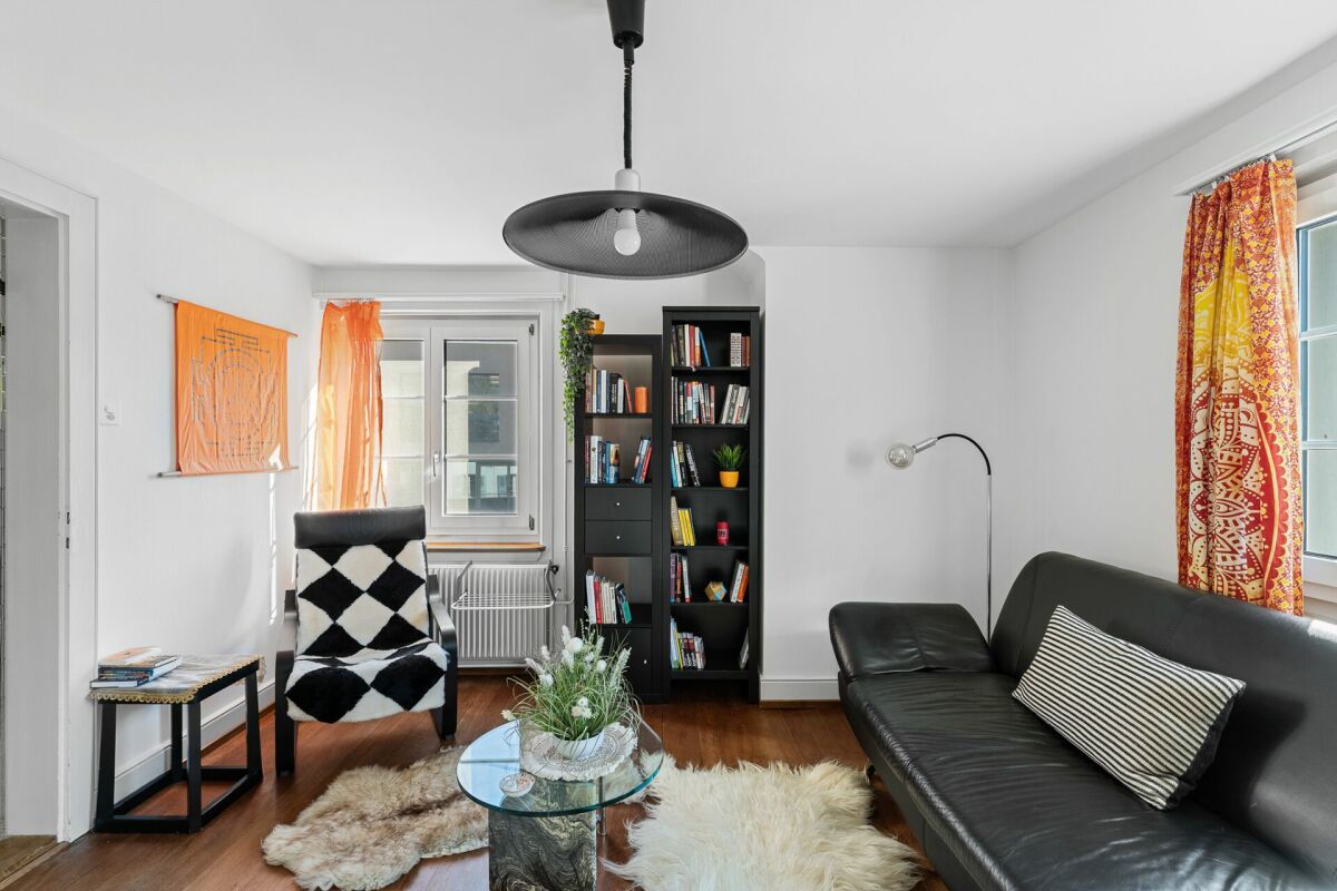 Wohnzimmer mit schwarzer Sofalandschaft und Bücherschrank