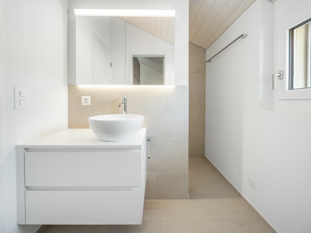 Helles, modernes Badezimmer mit Waschtisch und schmalem Duschbereich