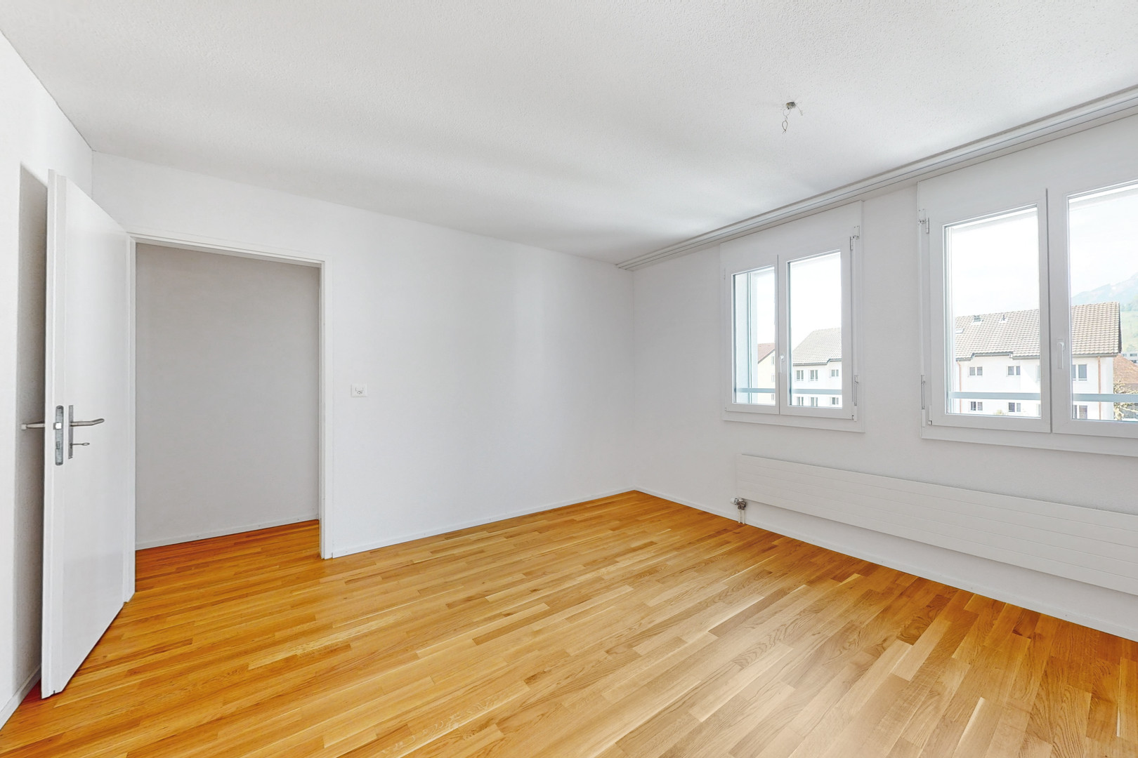 Heller leerer Raum mit Parkett und Fenstern