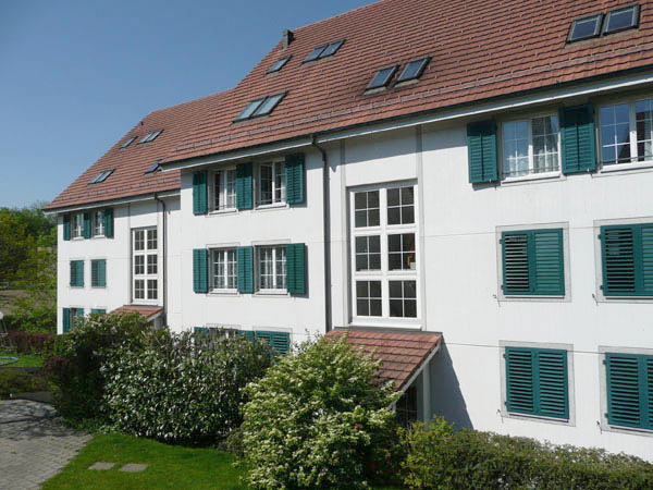 Mehrfamilienhaus mit grünen Fensterläden