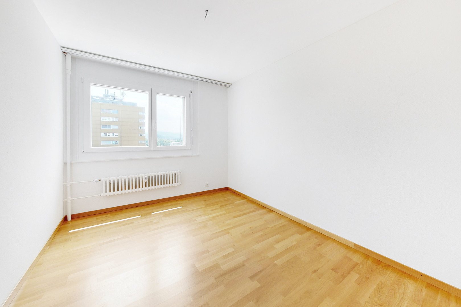 Heller leerer Raum mit Parkett und Fenster