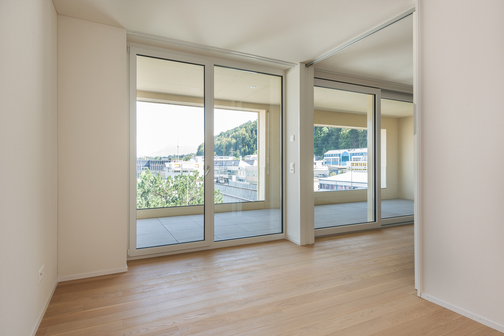 Heller leerer Wohnraum mit großem Balkon- und Bergblick