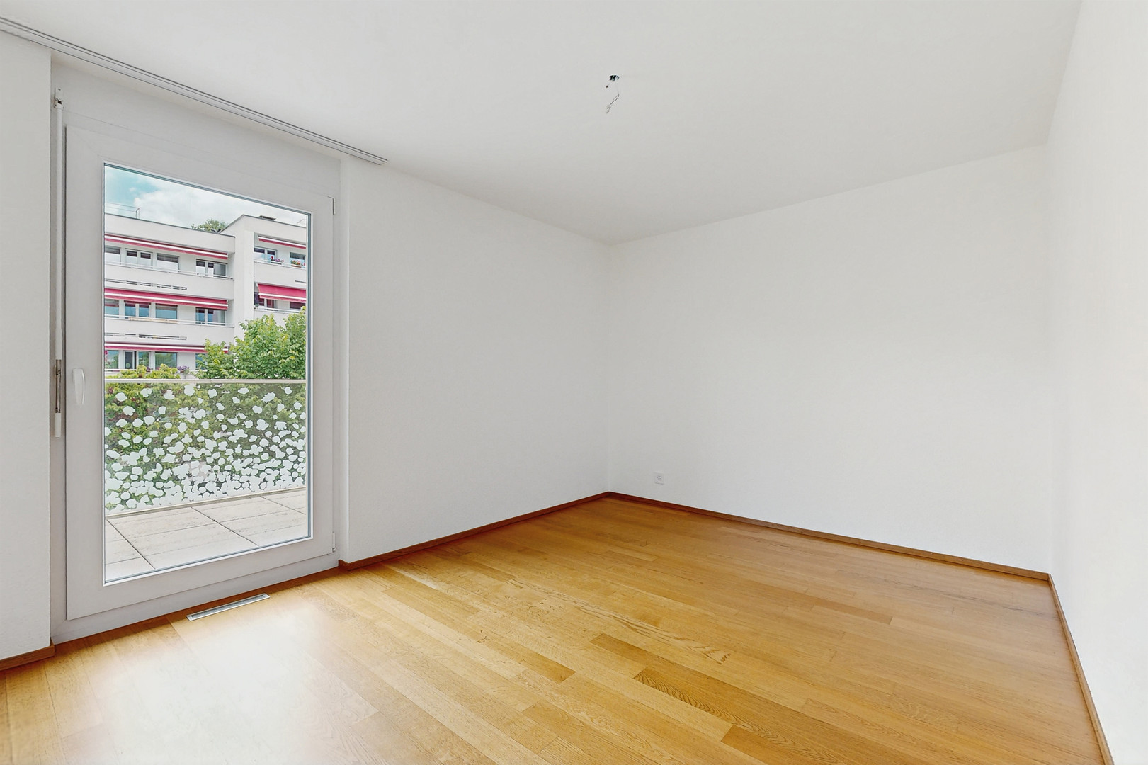 Leerer Wohnraum mit Balkonzugang
