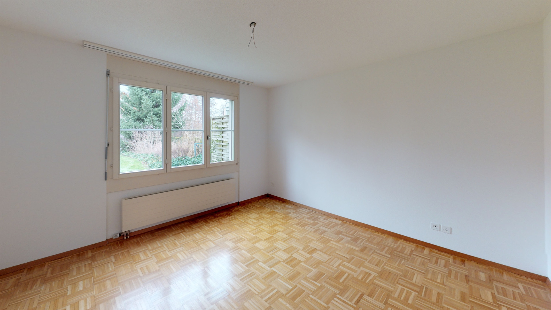 Leeres Zimmer mit Parkett und Fenster zum Garten