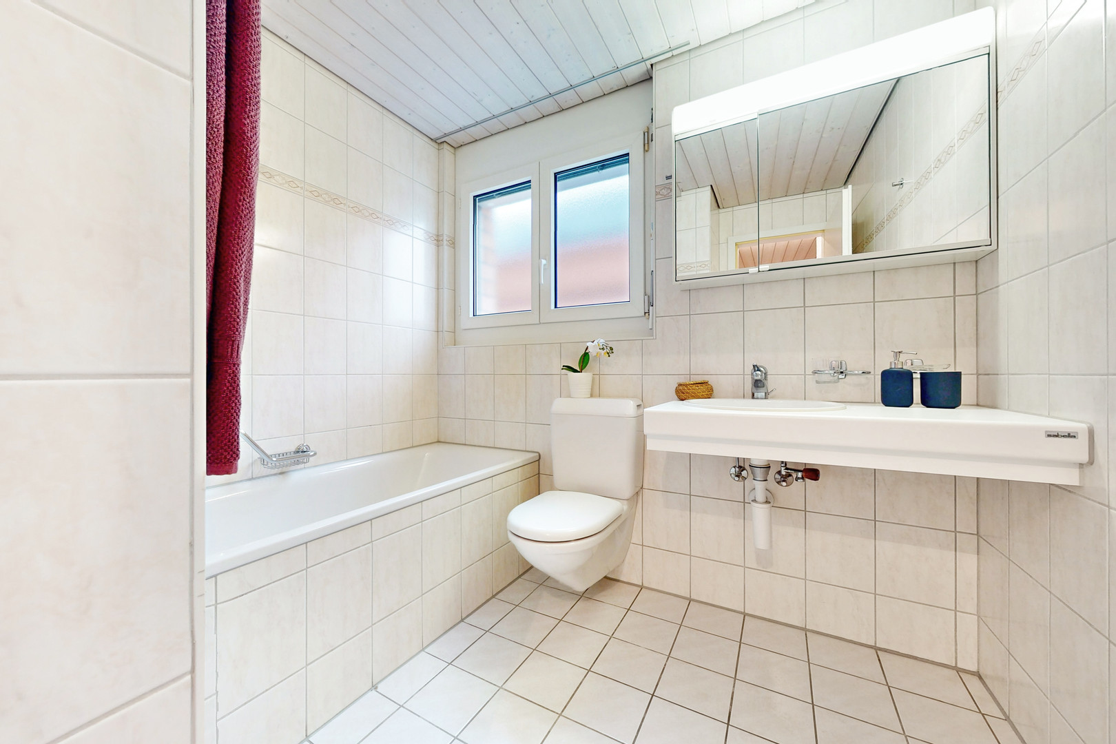 Hell gefliestes Badezimmer mit Wanne, WC und Waschtisch