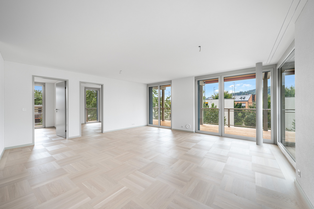 Großer leerer Wohnraum mit Balkon und bodentiefen Fenstern