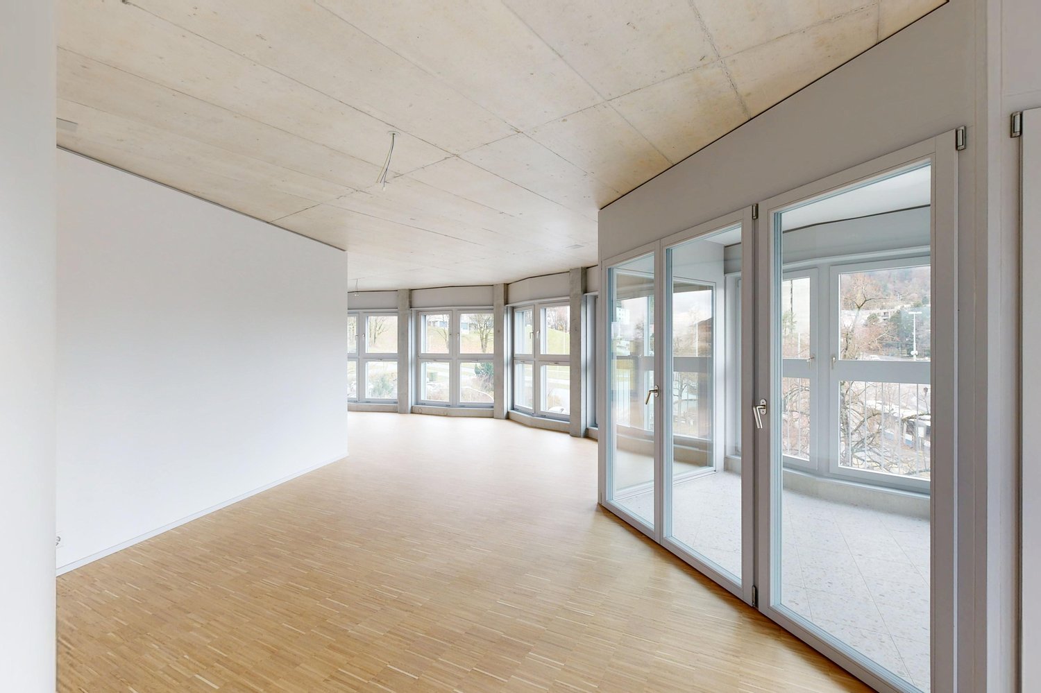 Großer leerer Wohnraum mit Fensterfront und Glastüren