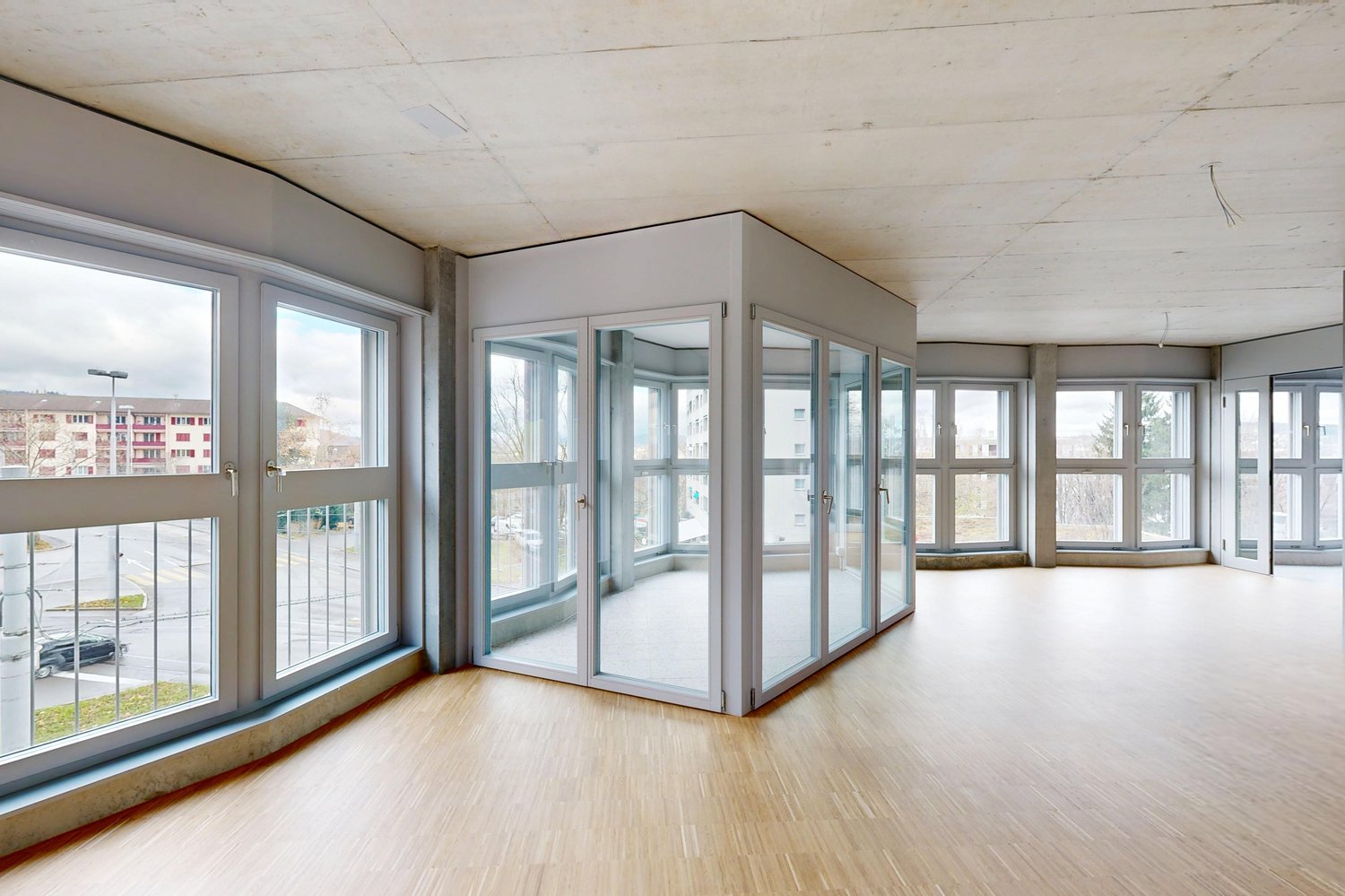Großer leerer Wohnraum mit vielen Fenstern